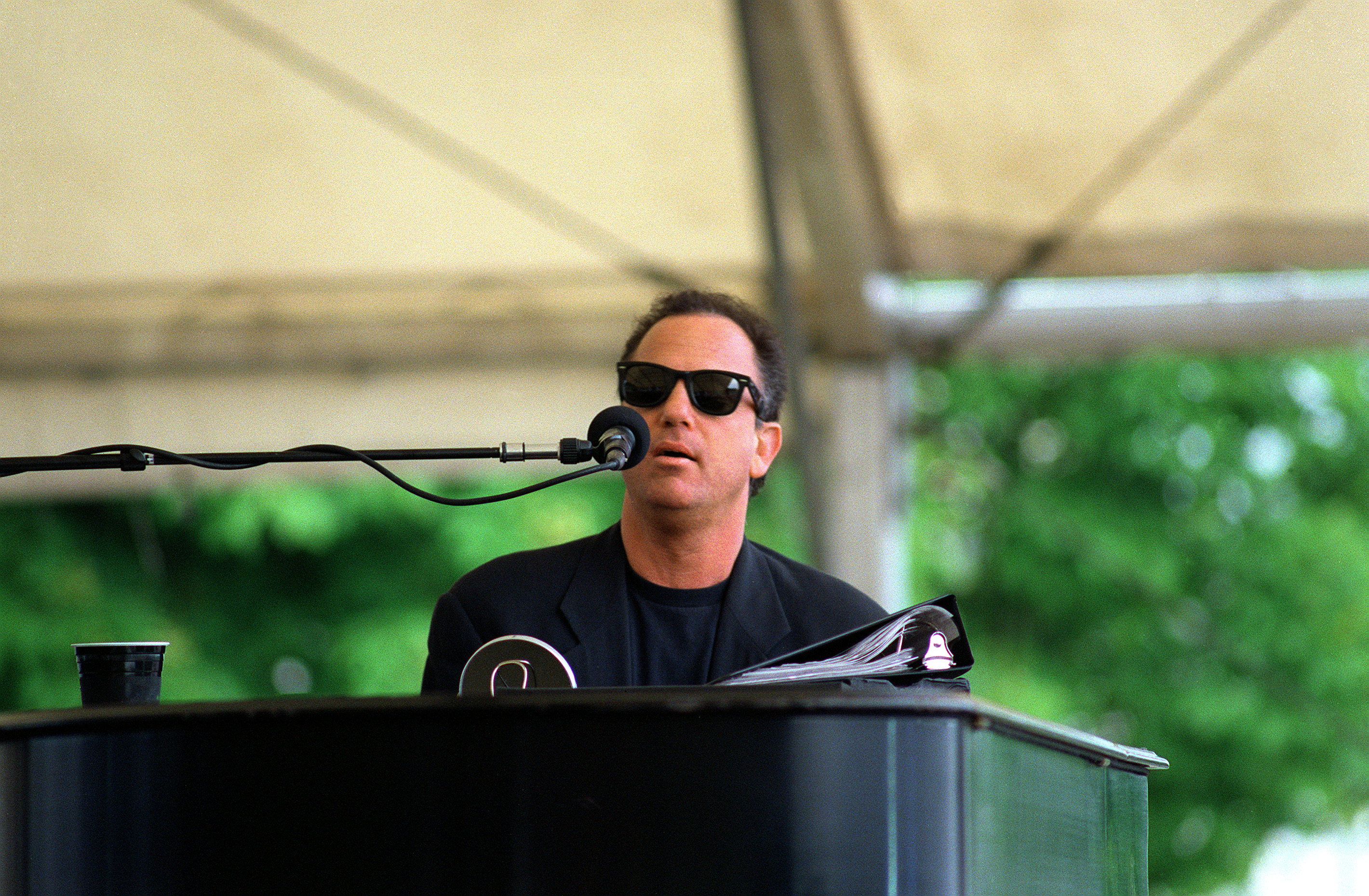Billy Joel playing piano outdoors at the USO concert in 1994.